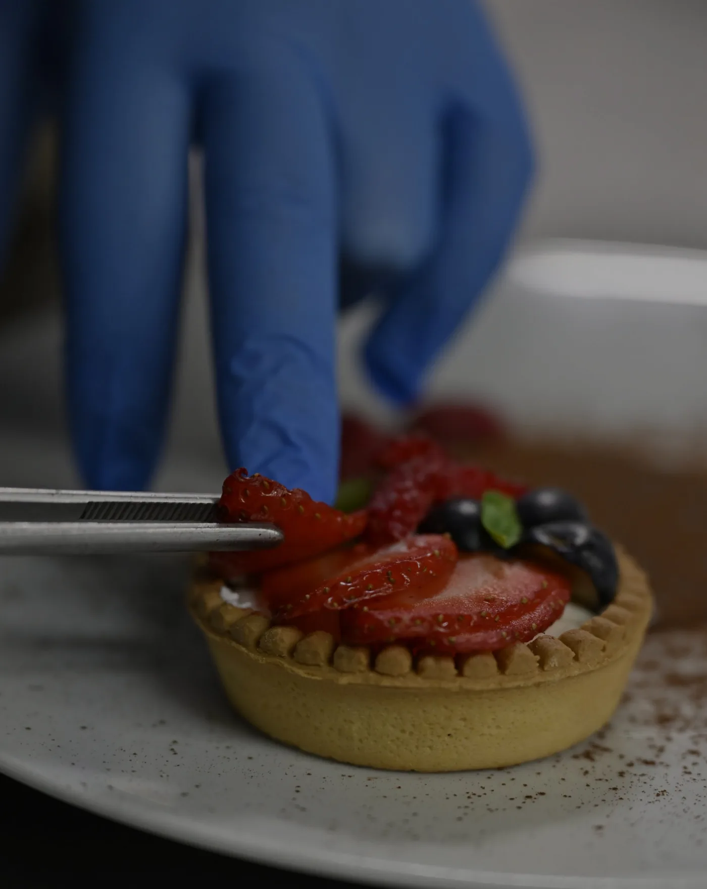 Mano dello chef che rifinisce un piatto: dettaglio di cucina e mestiere.